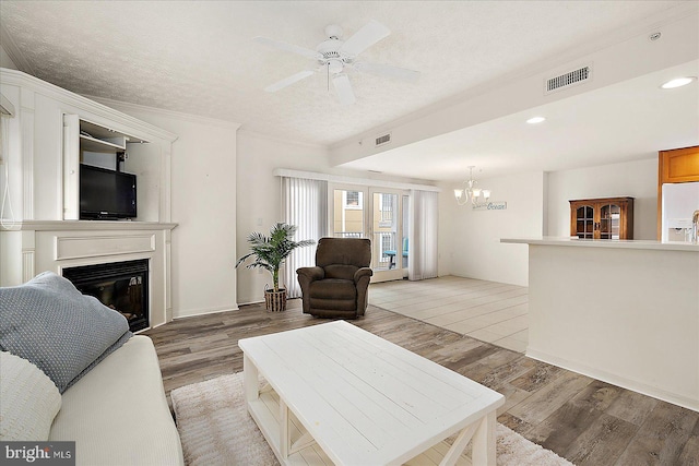 living area with light wood-type flooring, visible vents, a textured ceiling, and a glass covered fireplace