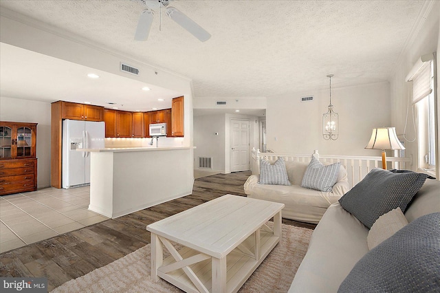 living room featuring visible vents, a textured ceiling, and light wood-style floors