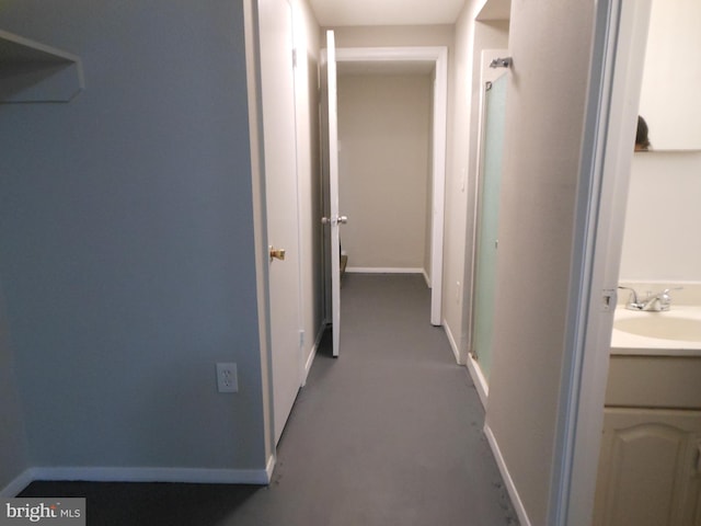 corridor featuring baseboards and a sink