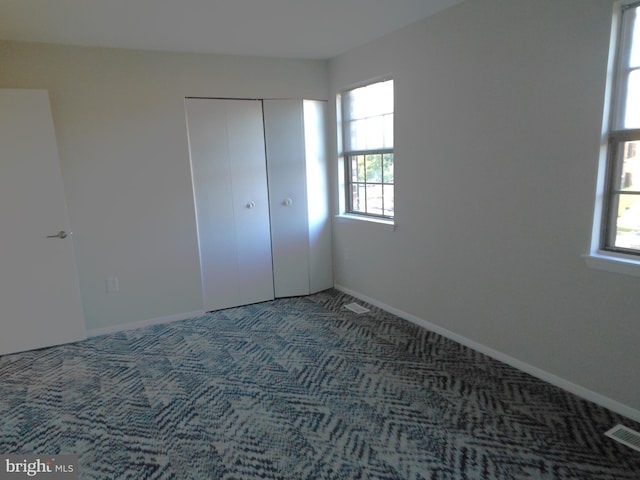 unfurnished bedroom with carpet flooring, baseboards, visible vents, and a closet