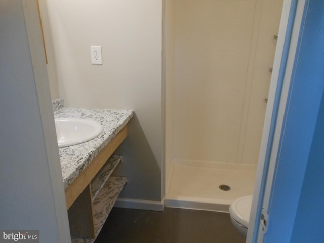 bathroom featuring baseboards, vanity, toilet, and a shower stall