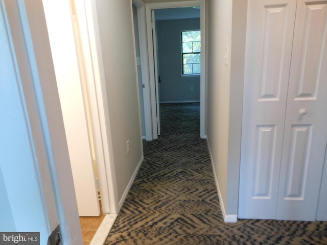 corridor with baseboards and light colored carpet