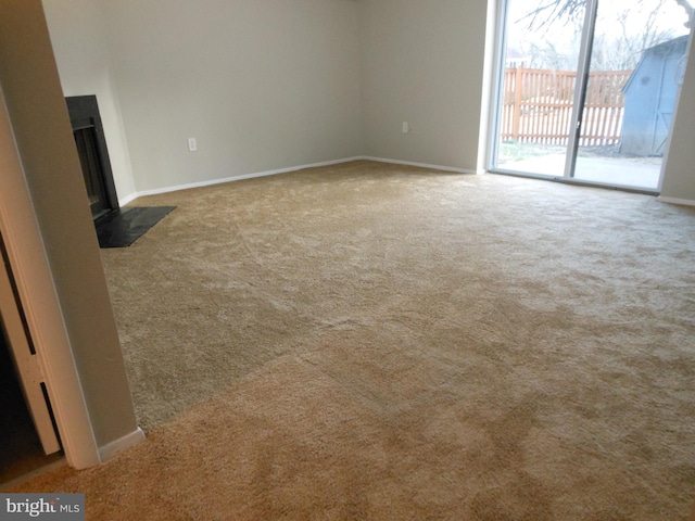 unfurnished living room with carpet flooring, baseboards, and a fireplace with flush hearth