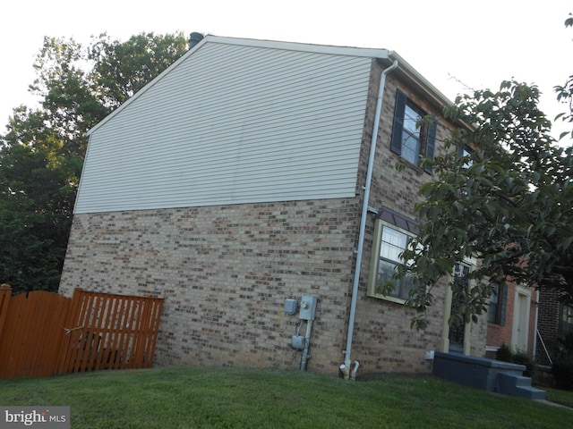 view of property exterior featuring brick siding and a yard