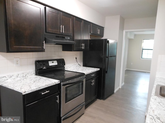 kitchen with backsplash, under cabinet range hood, stainless steel range with electric cooktop, freestanding refrigerator, and light wood-style floors