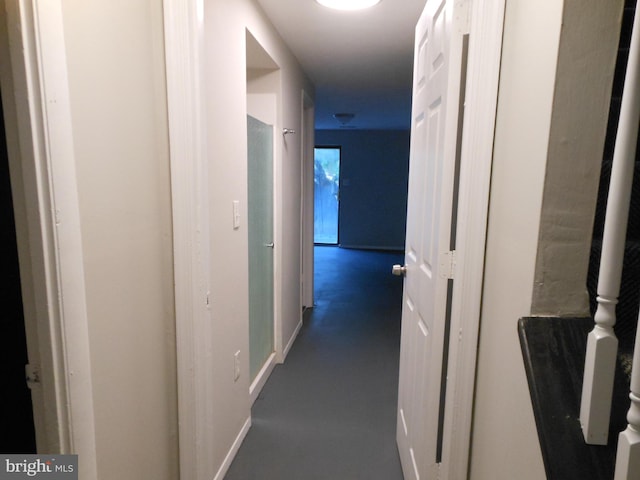 corridor with baseboards and concrete floors