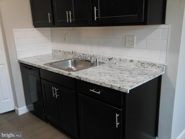 kitchen with decorative backsplash, dark cabinetry, black dishwasher, and a sink