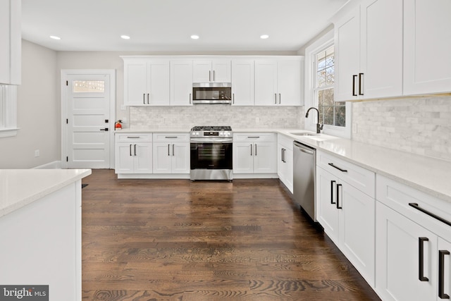 kitchen with backsplash, light countertops, stainless steel appliances, white cabinetry, and dark wood-style flooring