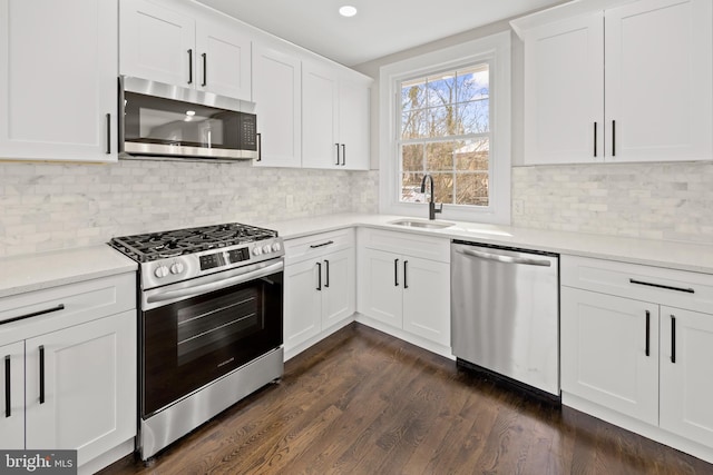 kitchen with a sink, stainless steel appliances, white cabinets, light countertops, and dark wood-style flooring