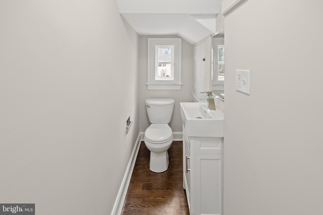 bathroom featuring toilet, lofted ceiling, wood finished floors, baseboards, and vanity