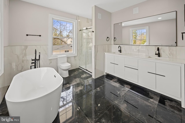 full bathroom with double vanity, marble finish floor, a shower stall, and a sink