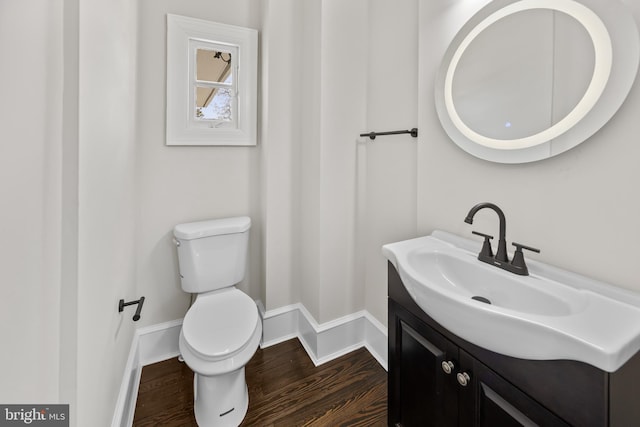 bathroom with toilet, vanity, baseboards, and wood finished floors