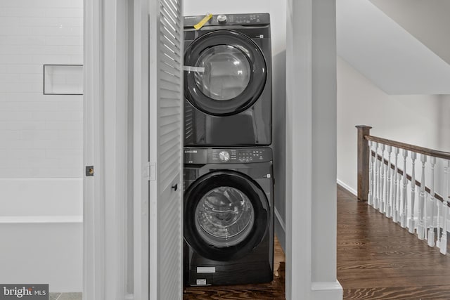 laundry area with laundry area, stacked washer and clothes dryer, and wood finished floors