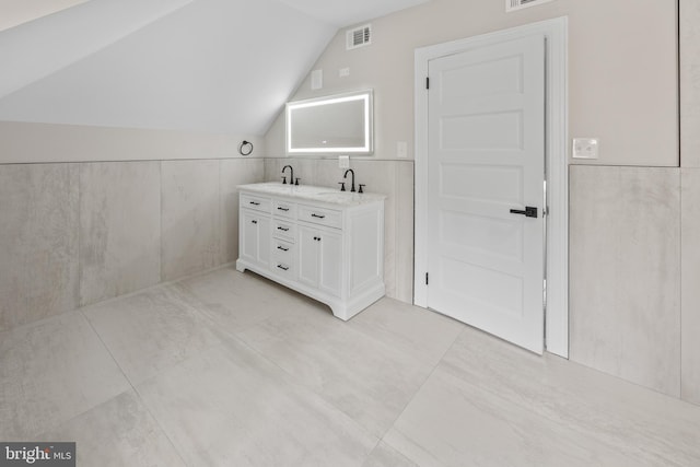 full bathroom with lofted ceiling, double vanity, visible vents, and a sink