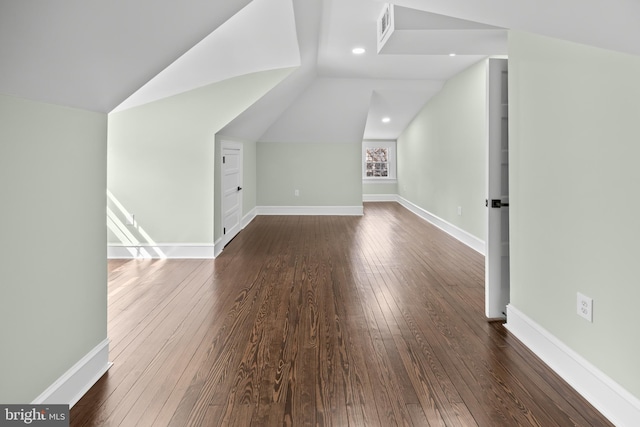 additional living space featuring dark wood-style floors, visible vents, baseboards, and lofted ceiling