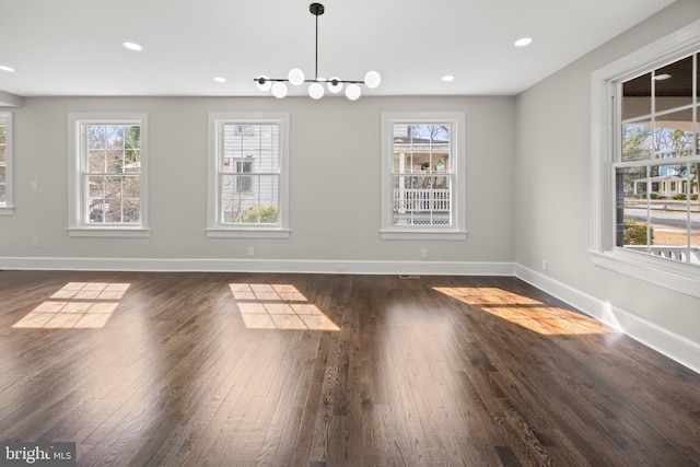 unfurnished dining area with dark wood finished floors, a healthy amount of sunlight, and baseboards