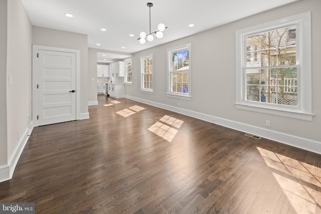 unfurnished living room featuring visible vents, baseboards, recessed lighting, dark wood-style flooring, and a notable chandelier