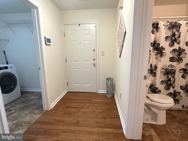 interior space with toilet, washer / clothes dryer, wood finished floors, and baseboards