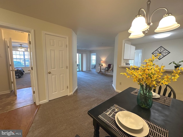 dining space featuring an inviting chandelier, baseboards, and dark colored carpet