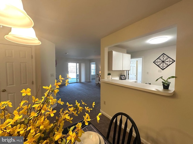 unfurnished dining area featuring baseboards and dark colored carpet