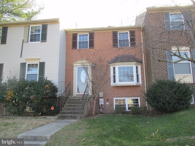 view of front of house featuring brick siding, a front yard, and entry steps