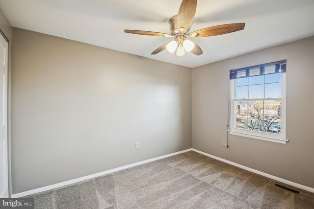 carpeted spare room with a ceiling fan, baseboards, and visible vents