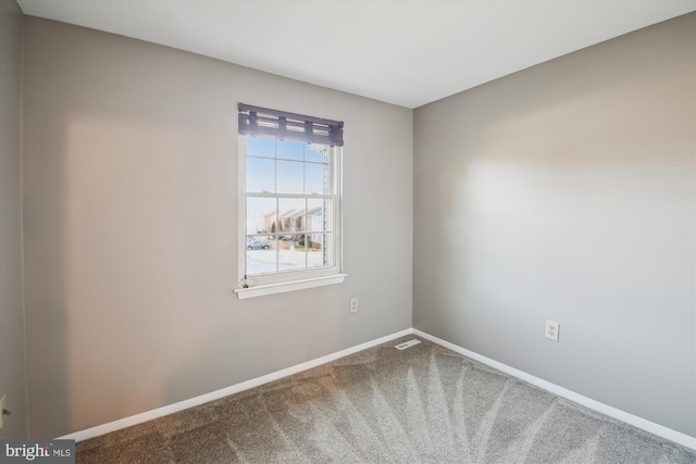 carpeted spare room with visible vents and baseboards