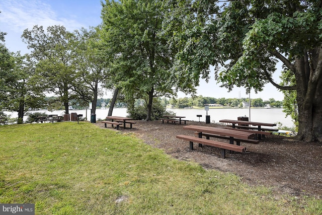 view of home's community with a dock, a yard, and a water view