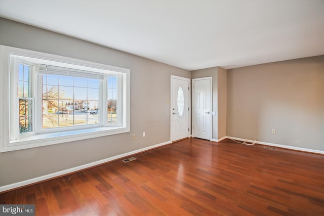 unfurnished room featuring visible vents, baseboards, and wood finished floors