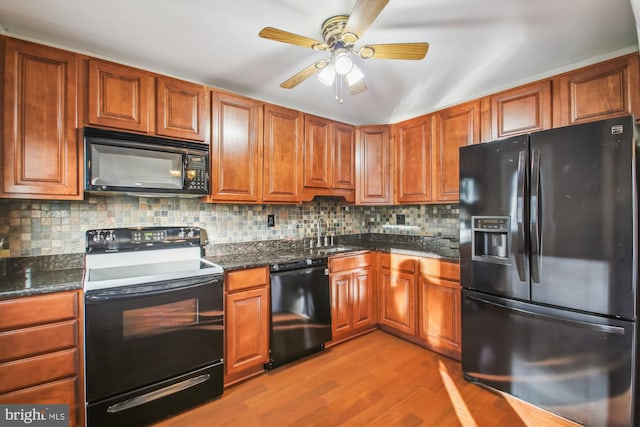 kitchen with decorative backsplash, black appliances, wood finished floors, and a sink