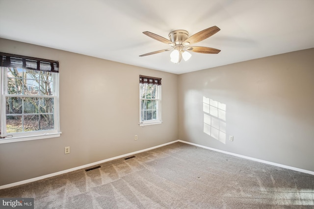 carpeted spare room with visible vents, a ceiling fan, and baseboards