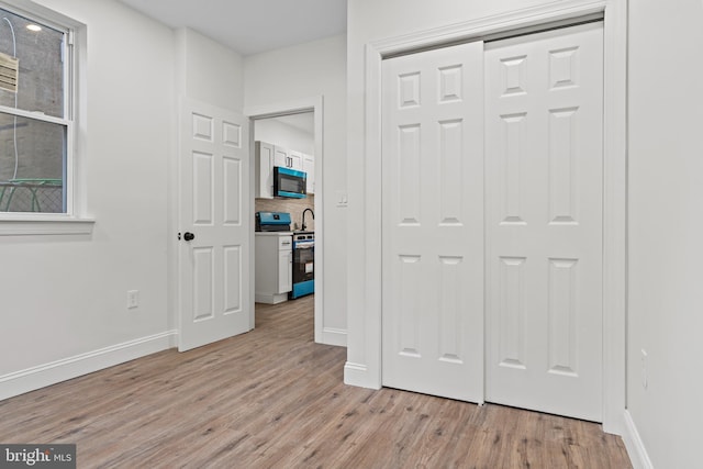 unfurnished bedroom featuring light wood-type flooring, baseboards, and a closet