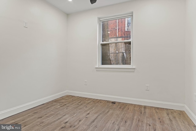 empty room with ceiling fan, wood finished floors, visible vents, and baseboards