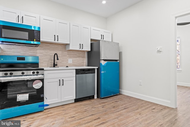 kitchen with tasteful backsplash, light countertops, light wood-style flooring, appliances with stainless steel finishes, and a sink