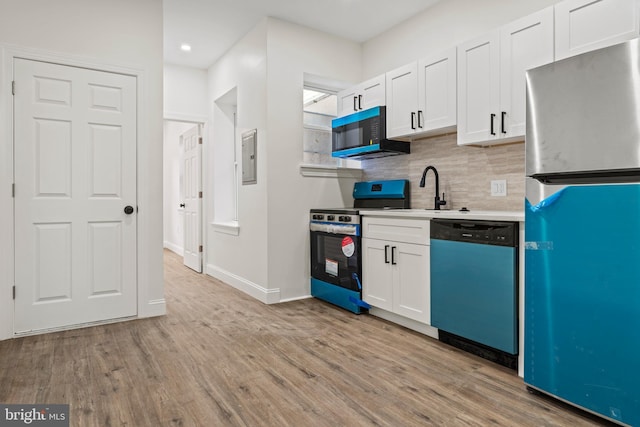 kitchen featuring a sink, decorative backsplash, stainless steel appliances, light wood-style floors, and white cabinetry