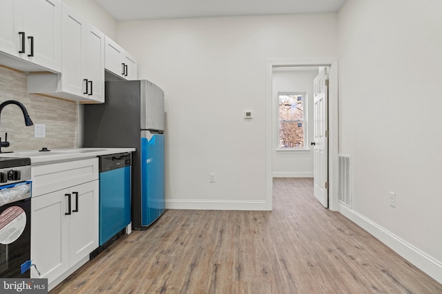 kitchen featuring visible vents, dishwashing machine, light wood-style flooring, decorative backsplash, and white cabinetry