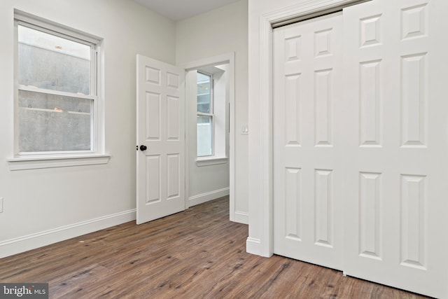 unfurnished bedroom with a closet, baseboards, and wood finished floors