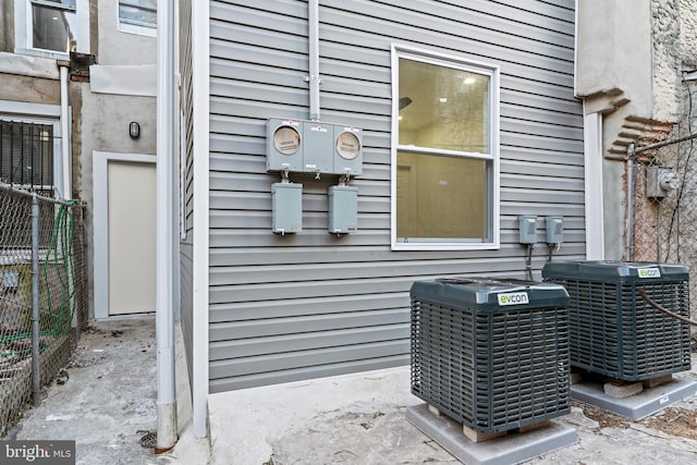 details featuring central AC unit, electric meter, and fence