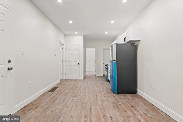 interior space featuring baseboards, light wood finished floors, recessed lighting, appliances with stainless steel finishes, and white cabinetry