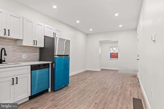 kitchen featuring tasteful backsplash, visible vents, dishwasher, light wood-style flooring, and a sink