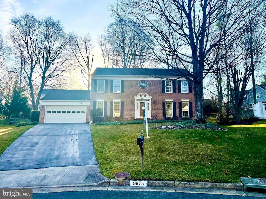 colonial home featuring a garage, brick siding, concrete driveway, and a front yard