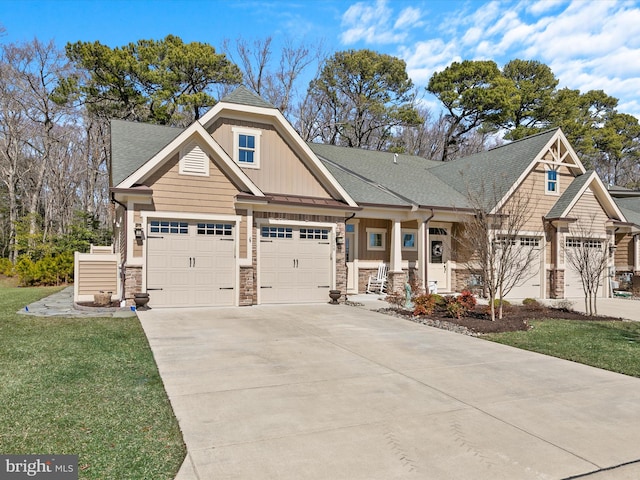 view of front of property featuring stone siding, board and batten siding, concrete driveway, a front yard, and a shingled roof