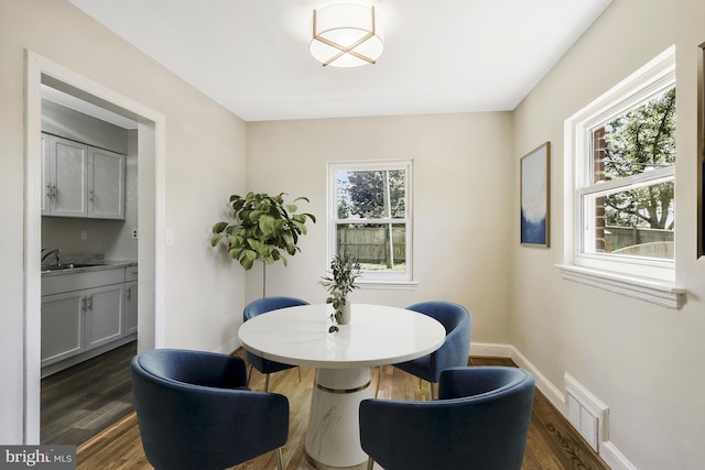 dining space with a wealth of natural light, visible vents, baseboards, and dark wood finished floors