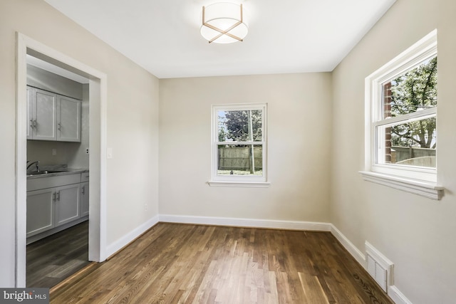 unfurnished dining area featuring wood finished floors, baseboards, visible vents, and a wealth of natural light