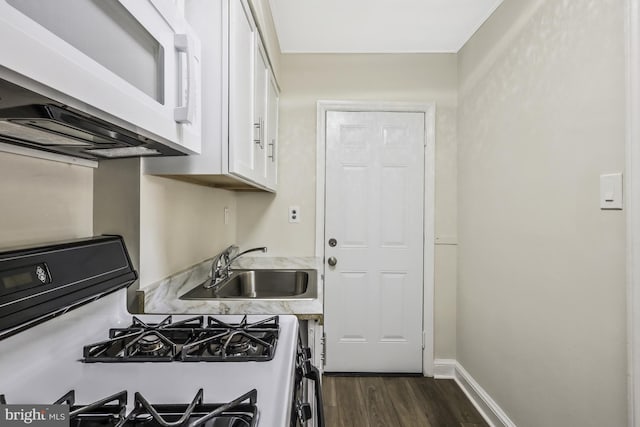 kitchen with dark wood-style floors, white microwave, white cabinetry, a sink, and range with gas cooktop