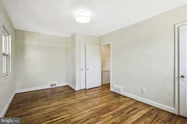 unfurnished bedroom featuring wood finished floors, visible vents, and baseboards