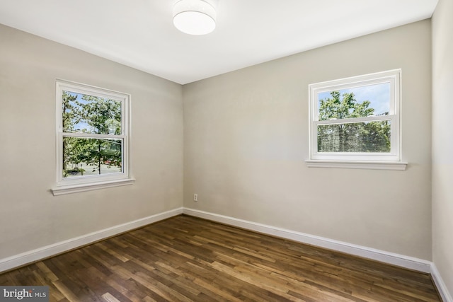 spare room with baseboards and dark wood-style flooring