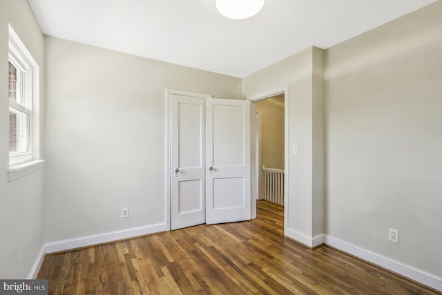 unfurnished bedroom featuring wood finished floors and baseboards