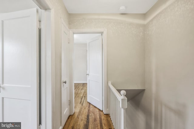 hallway featuring an upstairs landing and wood finished floors