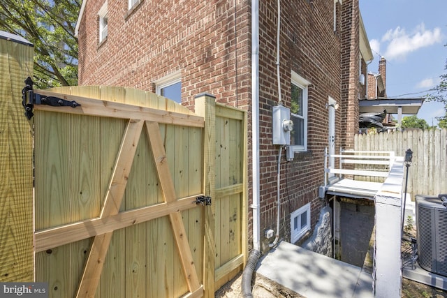 view of home's exterior featuring cooling unit, fence, and brick siding